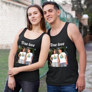 May include: Two people wearing black tank tops with the text "True love" printed on the front. Each tank top features a framed image of a couple. The tank tops are a dark charcoal color.