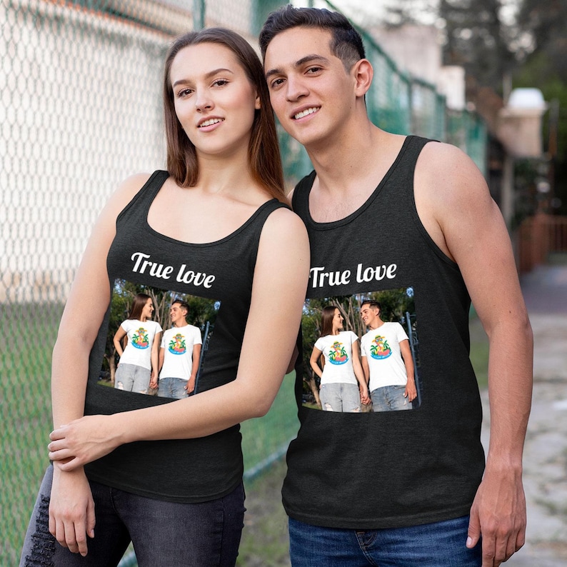 May include: Two people wearing black tank tops with the text "True love" printed on the front. Each tank top features a framed image of a couple. The tank tops are a dark charcoal color.