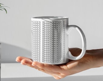 May include: White ceramic mug with the words "HIDDEN MESSAGE YOUR" printed in a repeating pattern in grey. The mug is held in a person's hand.