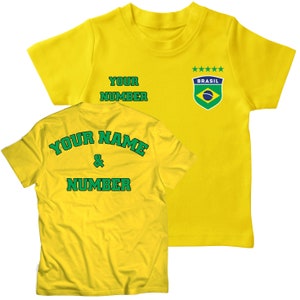 May include: Yellow soccer jersey with green and blue details. The front of the jersey has the text "YOUR NUMBER" and a small patch with the text "BRASIL" and five stars. The back of the jersey has the text "YOUR NAME & NUMBER" in green.
