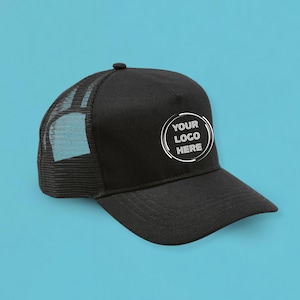 Op de afbeelding: Zwarte truckerpet met een mesh achterkant en een gebogen klep. De pet heeft een wit cirkelvormig logo met de tekst "YOUR LOGO HERE". De pet staat tegen een effen blauwe achtergrond.