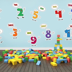 May include: Colorful cartoon numbers one through ten with speech bubbles above each number. The numbers are on a light blue wall. A pile of colorful wooden blocks is in the foreground.