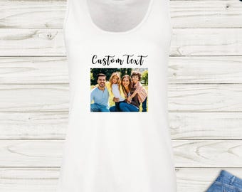 May include: White tank top with a family photo and the words "Custom Text" in black script. The photo shows a family of four smiling in a park setting. The tank top is sleeveless and has a scoop neck.