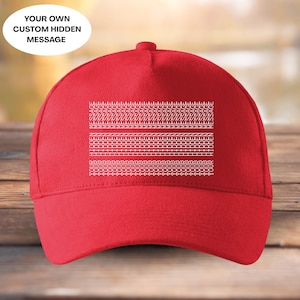 May include: A vibrant red baseball cap with a curved peak. The cap displays a series of white embroidered patterns. Above the peak is a white oval with the text "YOUR OWN CUSTOM HIDDEN MESSAGE".