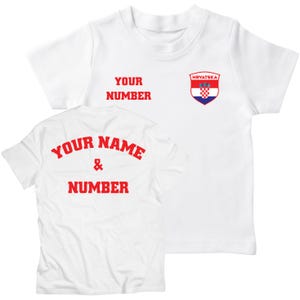 K&ouml;nnte beinhalten: Wei&szlig;es T-Shirt mit rotem Text, der auf der R&uuml;ckseite "YOUR NAME & NUMBER" und auf der Vorderseite "YOUR NUMBER" sowie ein kroatisches Wappen lautet.