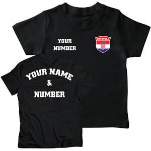 K&ouml;nnte beinhalten: Zwei schwarze T-Shirts, eines mit dem Text "YOUR NAME & NUMBER" und das andere mit dem Text "YOUR NUMBER" und einem kroatischen Wappen mit dem Text "HRVATSKA".