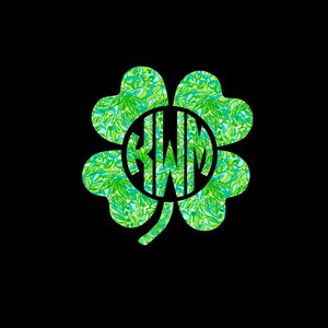 May include: A green four-leaf clover with a circle in the center. The circle contains the letters "KWM" in a white font.