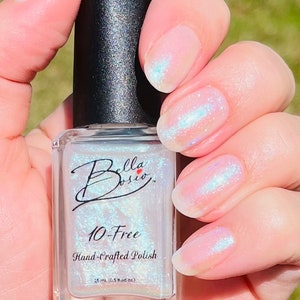 May include: A clear glass bottle of iridescent nail polish with a black cap. The bottle label reads "Bella Bosio 10-Free Hand-Crafted Polish 15 ml (0.5 fluid oz)".
