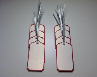 May include: A set of ten blank gift tags with red borders and silver ribbon. The tags are stacked and ready to be used for gift giving.
