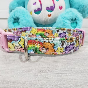 May include: A pink and white dog collar with a colorful Care Bears print featuring rainbows, stars, and Care Bears characters.