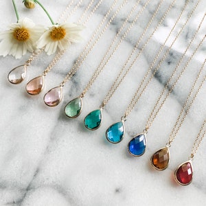 May include: Nine gold necklaces with teardrop-shaped glass pendants in various colors, including clear, pink, green, blue, and red.