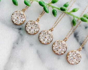 May include: Five gold necklaces with round pendants featuring a cluster of clear cubic zirconia stones arranged in a flower shape.
