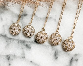 May include: Five gold necklaces with round pendants featuring a flower design with clear cubic zirconia stones.