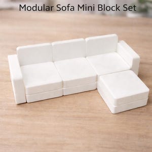 May include: A white modular sofa mini block set. The set includes a sofa with three seat cushions and two armrests, plus a separate ottoman. The text "Modular Sofa Mini Block Set" is printed on the top.