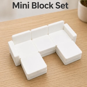 May include: A white modular sofa mini block set arranged on a light wood surface. The set includes several square and rectangular blocks that can be configured into different sofa shapes. The text "Modular Sofa Mini Block Set" is displayed at the top.