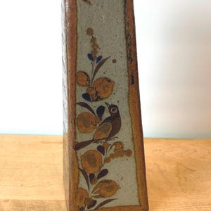 May include: A rectangular ceramic vase with a bird and floral design. The vase has a light gray background with brown accents and a bird perched on a branch. The vase is approximately 10 inches tall.