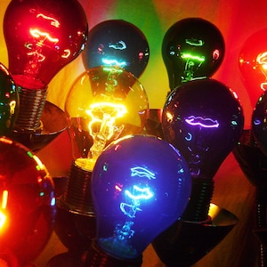 May include: A group of colorful light bulbs with different colored glass, including red, green, blue, and yellow. The bulbs are lit and casting a warm glow.