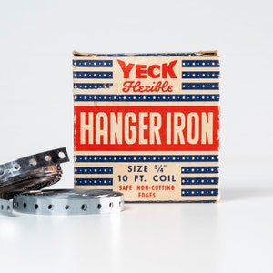 May include: A red, white, and blue box with the text "YECK Flexible HANGER IRON" and the details "SIZE 3/4" 10 FT. COIL SAFE NON-CUTTING EDGES". The box is next to a roll of silver hanger iron.