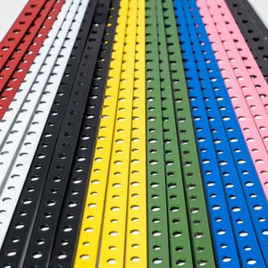 May include: A collection of colorful metal strips with evenly spaced holes. The strips are arranged in a rainbow pattern, with red, white, black, yellow, green, blue, and pink.