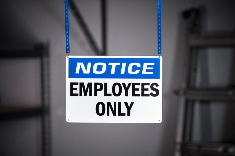 May include: A white sign with blue lettering that reads "NOTICE EMPLOYEES ONLY" hanging from two blue straps.