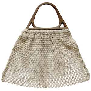 May include: A white crocheted net bag with a wooden handle. The bag is a traditional style with a wide, open top and a rounded bottom.