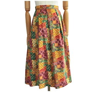 May include: A colorful patchwork skirt with a high waist. The skirt features a variety of patterned squares in shades of green, yellow, orange, and burgundy. The skirt is displayed on a mannequin.