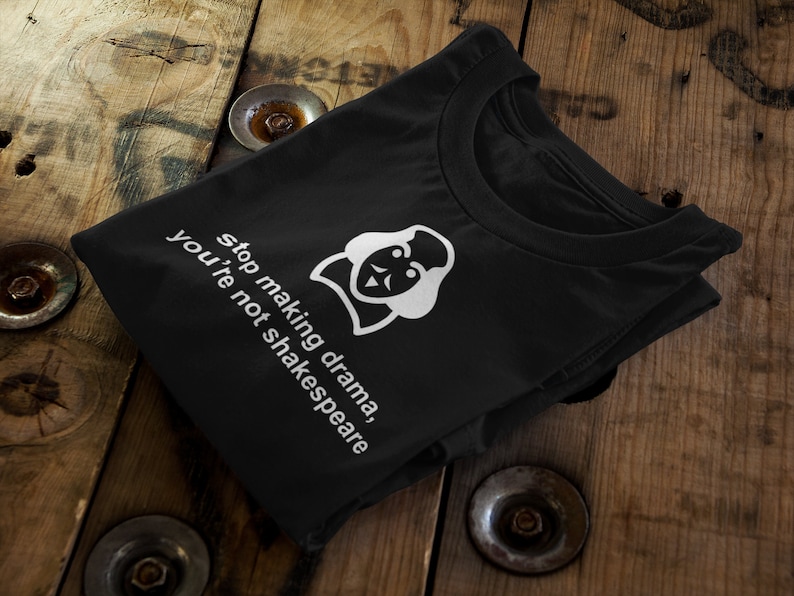 May include: Black t-shirt with a white graphic of a person's face with a mask and the text "stop making drama, you're not shakespeare".