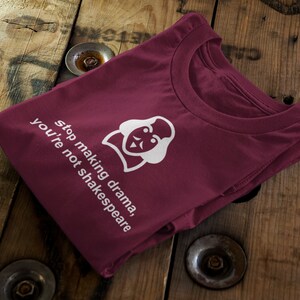 May include: Burgundy t-shirt with a white graphic of a person with a crown and the text "stop making drama, you're not shakespeare".