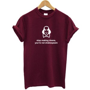 May include: Burgundy short-sleeved t-shirt with a white graphic of Shakespeare's face and the text "stop making drama, you're not Shakespeare".