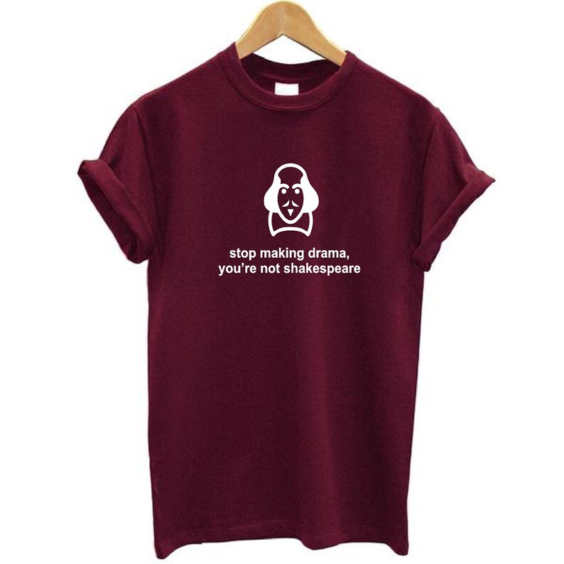 May include: Burgundy short-sleeved t-shirt with a white graphic of Shakespeare's face and the text "stop making drama, you're not Shakespeare".