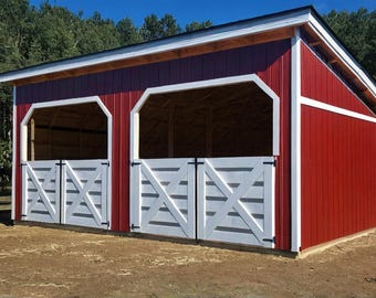 May include: A red barn with white trim and two stalls. The barn has a gabled roof and two white doors with an X-shaped design. The barn is set in a grassy area with trees in the background.