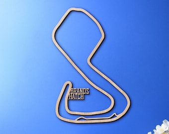 May include: A wooden cutout of the Brands Hatch race track, a popular motorsports circuit in England. The cutout is mounted on a blue wall, with a globe, books, and flowers in the foreground.