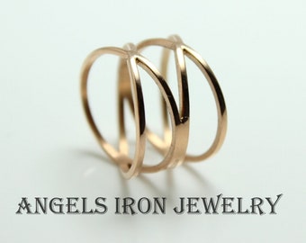 May include: A gold-toned ring with a geometric design. The ring is made of multiple thin bands that intersect and create a unique pattern.