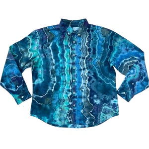 May include: A long-sleeved button-down shirt with a tie-dye pattern in shades of blue, teal, and white. The shirt has a classic collar, buttoned cuffs, and a front button closure. The fabric appears to be soft and lightweight.