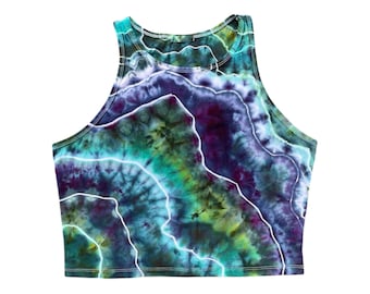 Pode incluir: Um top sem mangas tie-dye com comprimento cropped. O top é uma mistura vibrante de azul, verde, roxo e branco.