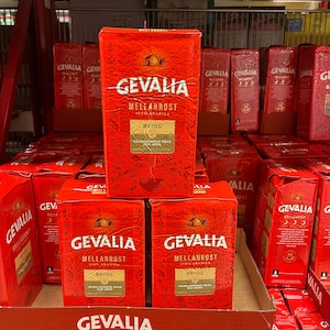 Könnte beinhalten: Ein Regal mit roten und weißen Kaffeepackungen der Marke "Gevalia" mit dem Aufdruck "Mellanrost 100% Arabica" auf der Vorderseite. Die Packungen sind pyramidenförmig gestapelt.