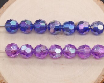 May include: A strand of iridescent purple and blue glass beads. The beads are faceted and have a hexagonal shape.