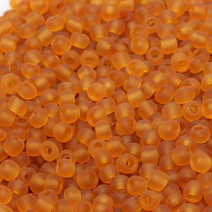 May include: A bowl filled with small, round, translucent amber-colored beads. The beads are opaque and have a slightly frosted finish.