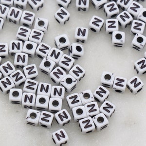May include: A large quantity of white plastic letter beads, all with the letter "N" in black.