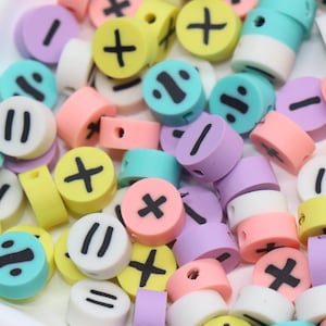 Pode incluir: Uma coleção de contas redondas e coloridas com vários símbolos matemáticos, incluindo sinais de mais, menos, multiplicação, divisão e igualdade. As contas são em cores pastel como amarelo, rosa, azul e roxo. Ideais para artesanato e criação de joias.