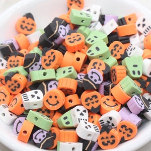 May include: A white bowl filled with colorful Halloween-themed beads. The beads feature various designs, including jack-o'-lanterns, ghosts, and smiling faces, in orange, black, green, white, and purple. These beads are perfect for crafting.