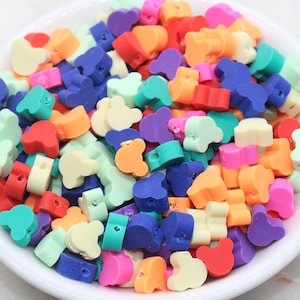 May include: A bowl filled with colorful plastic beads shaped like Mickey Mouse ears. The beads are in various shades of red, orange, yellow, green, blue, and purple.