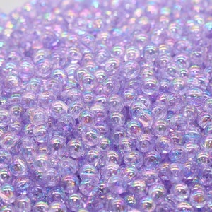 May include: A bowl filled with iridescent purple glass beads. The beads are small and round, and they have a subtle shimmer.