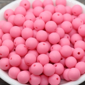 May include: A bowl filled with pink silicone beads. The beads are round and have a matte finish.