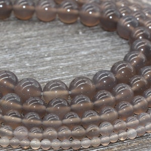 May include: A strand of gray agate beads in various sizes. The beads are round and have a translucent appearance.