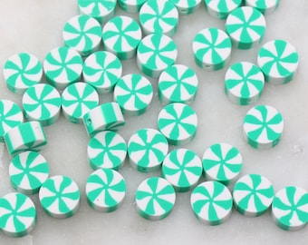 Puede incluir: Una colección de cuentas redondas en forma de bastón de caramelo, de color blanco y verde menta. Las cuentas tienen un patrón de espiral.