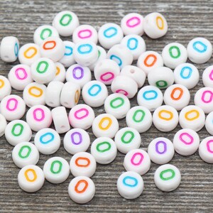 May include: A large pile of white plastic letter beads with the letter "O" in various colors. The beads are perfect for crafting and jewelry making.