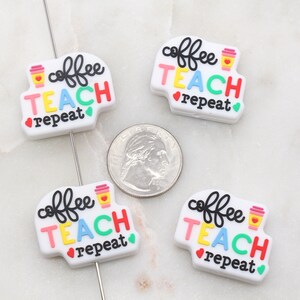 May include: Four white, round, silicone charms with the text "coffee teach repeat" in colourful letters. Each charm features a small cartoon coffee cup.