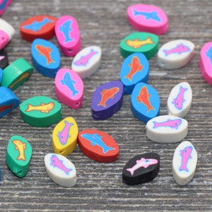 May include: Assortment of colorful oval-shaped beads with fish designs. The beads are made of plastic and come in a variety of colors, including blue, green, red, yellow, pink, purple, white, and black.