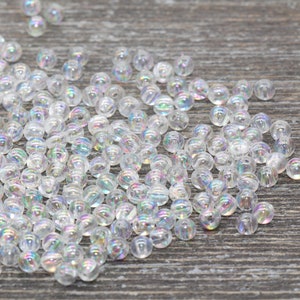 May include: A large pile of iridescent clear glass beads. The beads are round and have a slight shimmer to them.